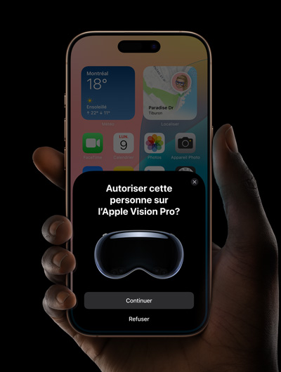Une main tenant un iPhone. L’écran de l’iPhone affiche une fenêtre avec le message ? Autoriser cette personne sur l’Apple Vision Pro? ? et les boutons Continuer et Refuser.