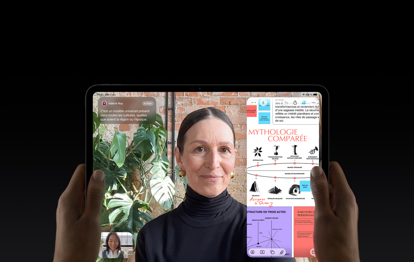Un iPad Pro, face avant, orientation paysage, noir infini, coins arrondis, bordure d’écran noire, mains tenant les c?tés gauche et droit, l’écran affiche une conversation FaceTime traduite en direct, à droite une app éducative montre une présentation sur les récits héro?ques avec du texte, des diagrammes et des notes manuscrites