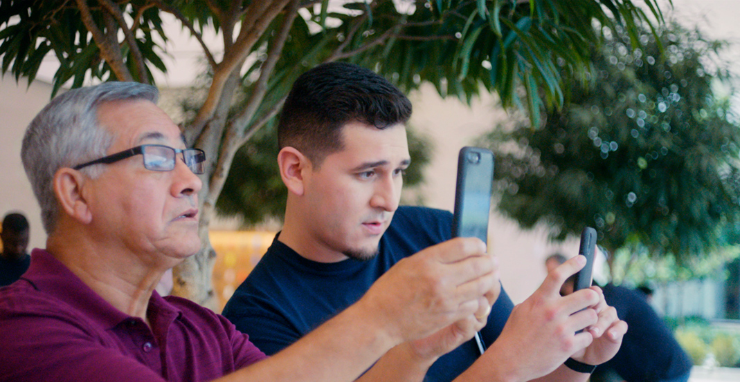 Technical Specialist Jeronimo laat aan een klant in de Apple?Store zien hoe de camera op een iPhone werkt.