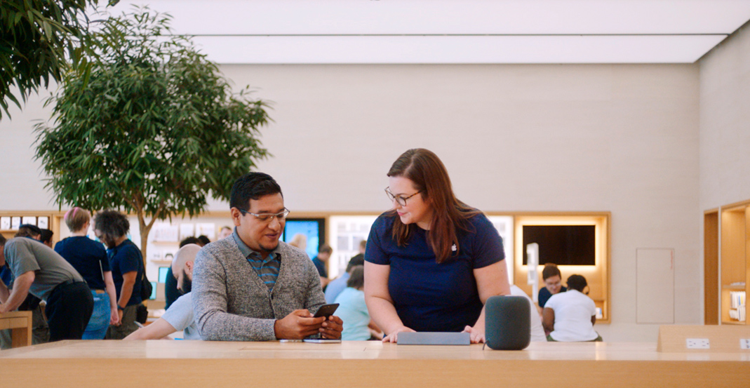 Apple?Store Genius Melissa helpt een klant met een probleem op zijn iPhone.