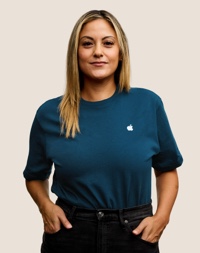 Portr?t eines l?chelnden Apple Retail Teammitglieds mit langen dunkelblonden Haaren.