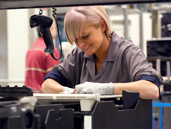 Twee productiemedewerkers inspecteren aluminium MacBook-behuizingen op anodiseerrekken van titanium.