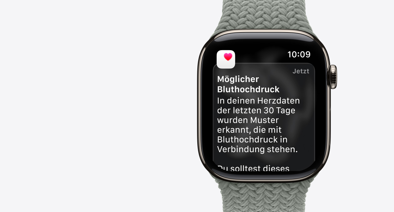 Apple Watch Series 11, Farbe Gold, Titangeh?use, Mitteilung: M?glicher Bluthochdruck, pinkes Herz in wei?em Feld, rechte Seitenansicht, Digital Crown, Armband, Geflochtenes Solo Loop Grüngrau