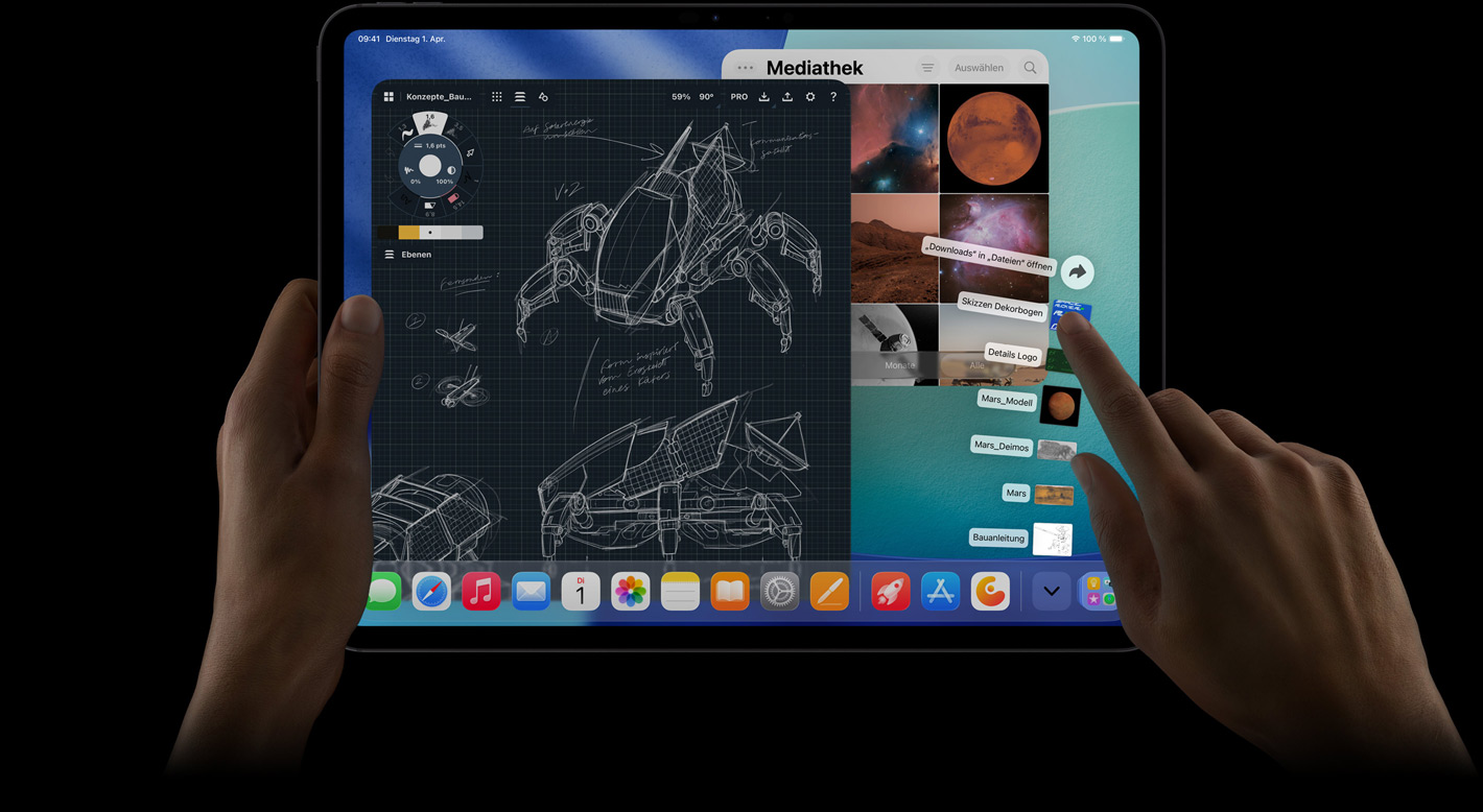 iPad Pro, Vorderansicht, Querformat, die rechte Hand bewegt sich über die nach oben aufgef?cherten Dateien im Downloads Ordner, das Display zeigt die iPadOS 26 Benutzeroberfl?che mit mehreren ge?ffneten Apps, darunter eine App zum Bearbeiten von Fotos mit detaillierten Roboterdesigns und handschriftlichen Anmerkungen sowie mehreren Designstufen und der Fotomediathek