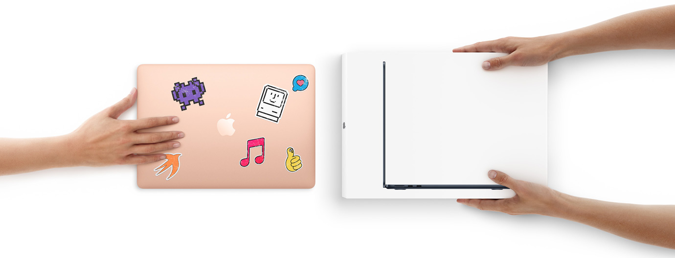 Een hand schuift een MacBook met stickers naar twee handen die een nieuwe verpakte MacBook vasthouden