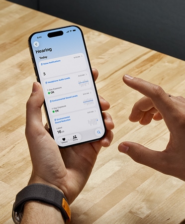 Egy AirPods Pro 2-felhasználó iPhone-t tart a kezében, mik?zben az új Hallásteszt funkciót használja