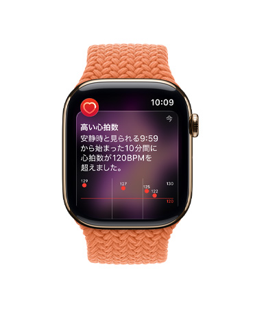 ゴールドチタニウムケースのApple Watch Series 11。高い心拍數(shù)の通知が表示され、ターメリックのブレイデッドソロループバンドが取りつけられている