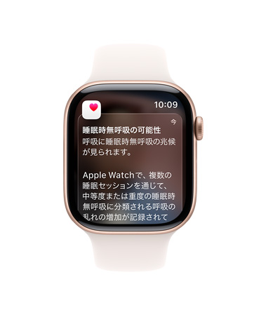 ローズゴールドアルミニウムケースのApple Watch Series 11。畫面に睡眠時(shí)無呼吸の通知が展開されている。右側(cè)面の外観、Digital Crown、ライトブラッシュのスポーツバンド