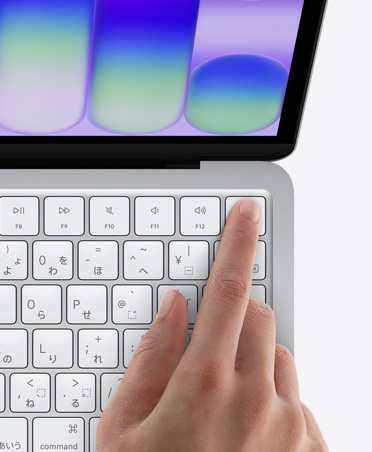 シルバーのMacBook Neo。キーボードの右上角にあるTouch IDセンサーに人の指が觸れている