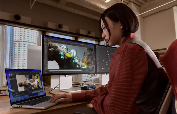 オフィスでStudio Display XDRに接続したMacBook Proを使って作業(yè)している人物