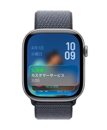 グレイのバンドを組み合わせたスペースグレイのApple Watch。畫面の下部に保留アシスタントの通知、左上に日付、右上に上下に重なった時(shí)刻が表示されている