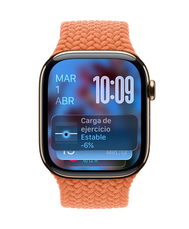 Apple Watch de titanio color oro con una correa trenzada color mandarina, cuya carátula muestra la fecha en la esquina superior izquierda, la hora con números angostos en la esquina superior derecha y debajo el widget Carga de Entrenamiento, todo con el dise?o translúcido de Liquid Glass