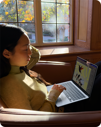 Cilvēks, kas sē? krēslā un strādā ar savu MacBook Air