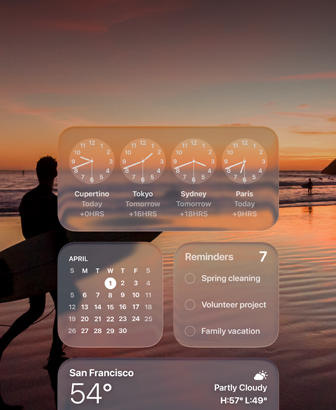 Clock, Calendar, Reminders un Weather vid?eti Liquid Glass dizainā uz macOS Tahoe ekrāna, un tiem fonā ir kadrs, kurā sērfotājs pastaigājas pa pludmali saulrietā