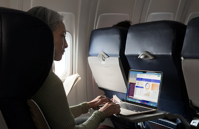 A person working on their MacBook?Air while in an airplane seat