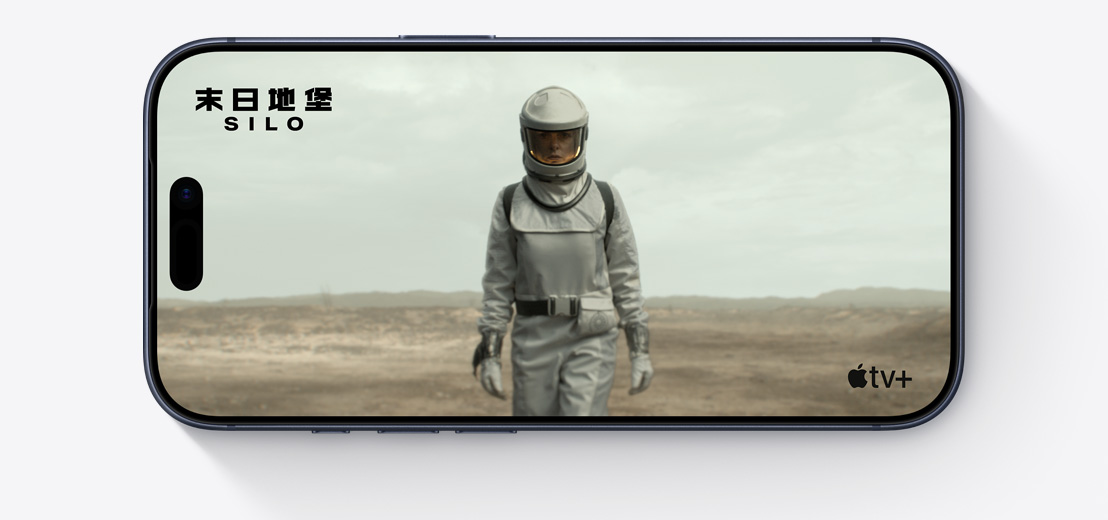 橫放的 iPhone，機(jī)身正面，螢?zāi)伙@示 Apple TV 劇集《末日地堡》(Silo) 的劇照，角色身穿太空衣