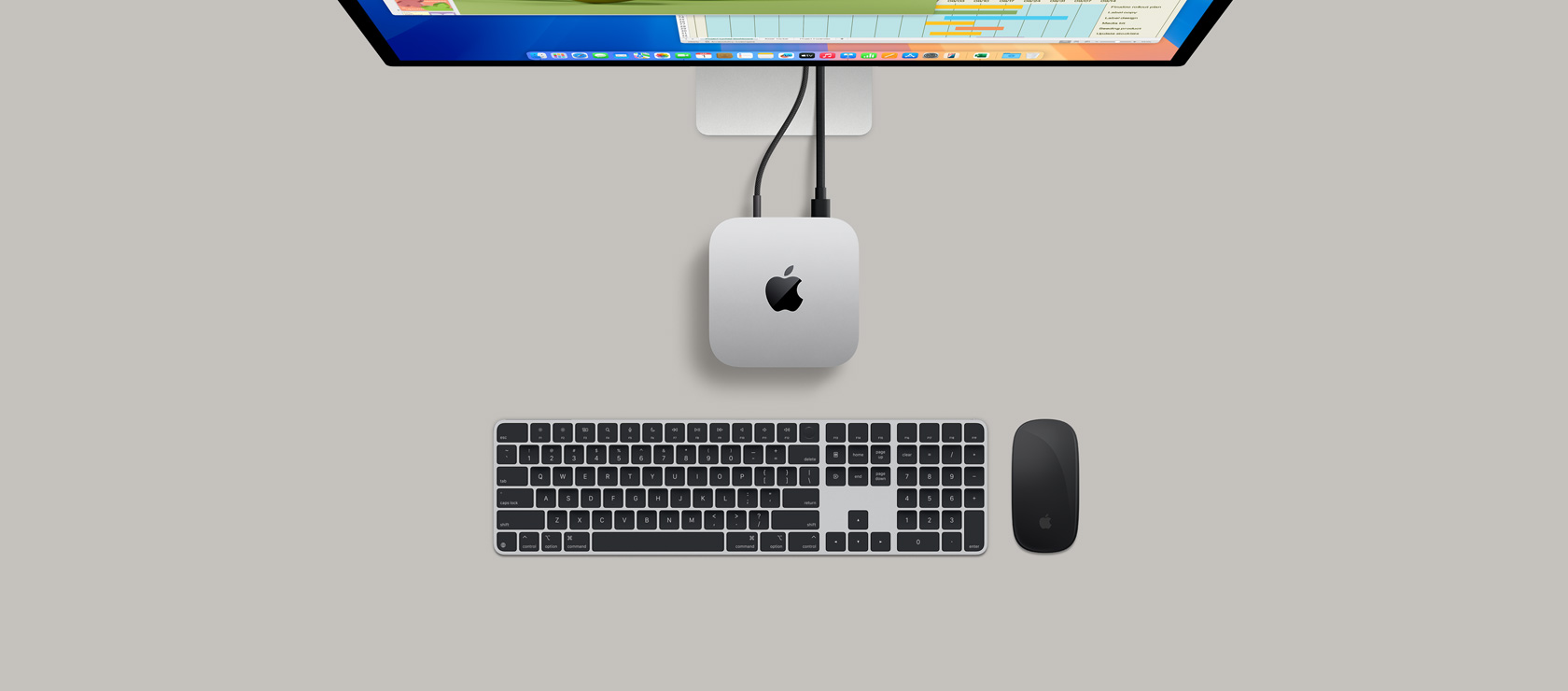 俯視圖展示銀色 Mac mini 連上顯示器，螢?zāi)伙@示打機(jī)場(chǎng)面，旁邊放有無(wú)線鍵盤(pán)、遊戲手掣和藍(lán)色 AirPods Max。