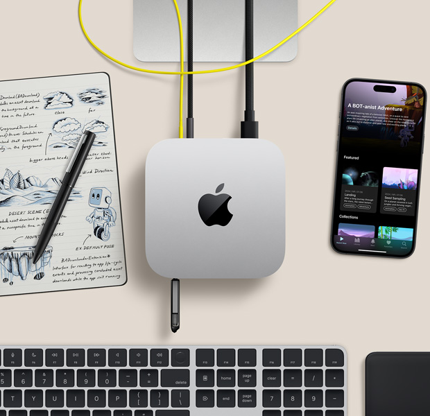 桌上的銀色 Mac mini 俯視圖，配有連接線和連在連接埠的快閃儲(chǔ)存，旁邊放著無(wú)線鍵盤(pán)、觸控板、iPhone 和筆記簿
