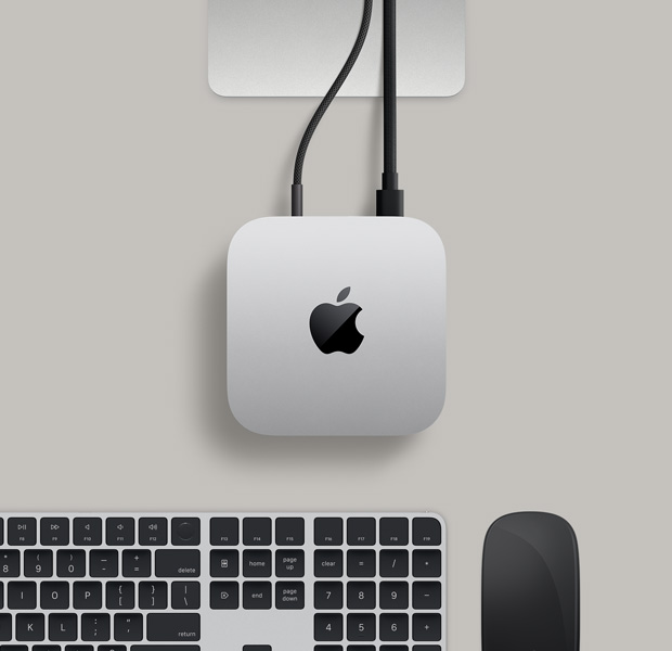 銀色 Mac mini 俯視圖，兩條連接線從背面插口連接至一部顯示器，旁邊放有黑色精妙滑鼠和黑色精妙鍵盤(pán)。