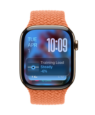 金色鈦金屬 Apple Watch 配上柑橘色編織錶帶，錶面的左上角顯示日期，右上角是以數(shù)字疊放方式顯示的時(shí)間，下方則是訓(xùn)練負(fù)荷量小工具，全以半透明的 Liquid Glass 設(shè)計(jì)呈現(xiàn)