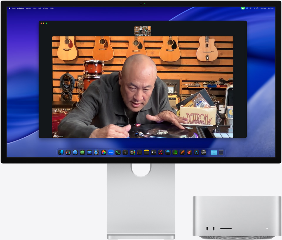 Na displeji Studio Display XDR, pod ktorym je zasunuty Mac Studio, prebieha videohovor, ktorého ú?astník si v obchode s hudobnymi nástrojmi prezerá vystaveny gramofón
