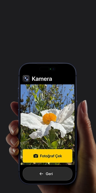 Kadraj?nda beyaz ?i?ek bulunan Kamera uygulamas?n?n basitle?tirilmi? arayüzünü, “Foto?raf ?ek” dü?mesini ve alt?ndaki “Geri” dü?mesini g?steren iPhone 17 Pro ekran?
