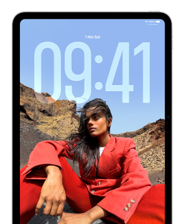 iPad Kilit Ekran?’nda, oturan bir ki?i foto?raf?n?n arka plan?nda büyük rakamlarla saat g?rünüyor