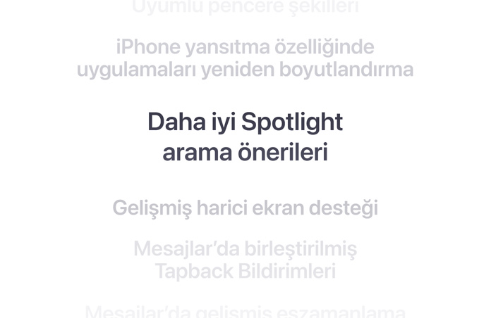 Dikey bir ?zellikler listesi, ortada kal?n harflerle “Daha iyi Spotlight arama ?nerileri” g?steriliyor. Etraf?ndaki di?er ?zellikler arka planda a?a?? ve yukar? do?ru silikle?iyor.