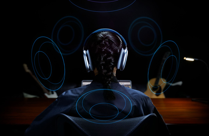Vista trasera de la cabeza de una persona que usa unos AirPods Max de Apple y dibujos alrededor de su cabeza que indican que está escuchando Audio Espacial