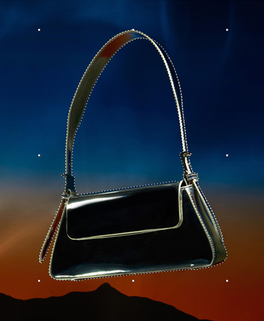 Una cartera negra delineada con líneas discontinuas, herramienta de selección, edición de imágenes, fondo de atardecer con silueta de monta?as